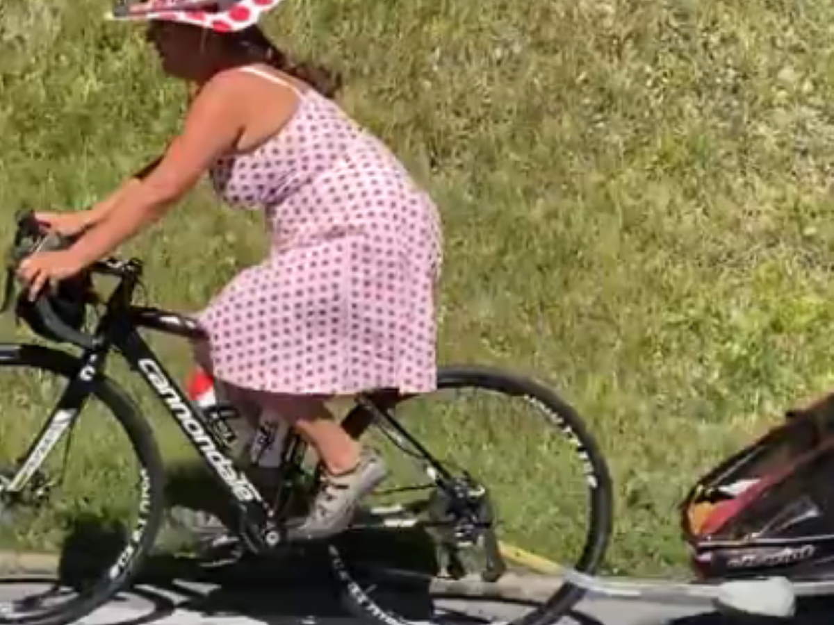 Mother in polka-dot jersey on a Cannondale road bike pulling her kid uphill